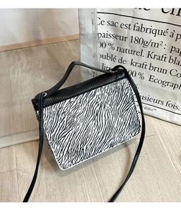 Détail du sac à bandoulière zébré avec rabat en cuir noir et finitions dorées chic