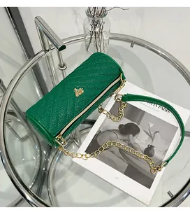 Detailed close-up of dark green cylindrical bag with V-shaped quilted leather and gold logo