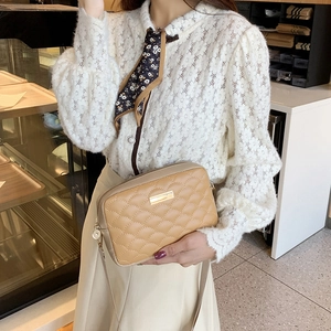 Khaki quilted crossbody bag for women with gold trim shown on a model in a cafe setting