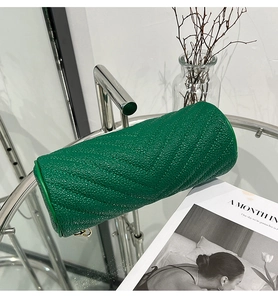 Close-up of green cylinder bag featuring V-shaped quilted leather texture and modern design
