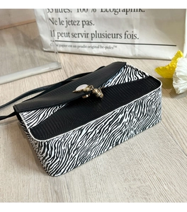 Détail du sac à main zébré avec rabat texture lézard et pendentif gland doré décoratif
