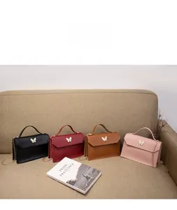 Close-up of four mini square bags with gold butterfly clasps and chain straps on sofa