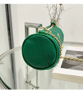 Close-up of emerald cylinder bag featuring lychee grain texture and gold chain strap
