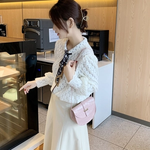 Pink crocodile pattern mini saddle bag for women shown with an elegant cafe outfit