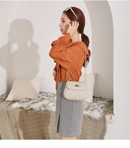 Lifestyle shot of beige quilted chain bag with gold twist lock and diamond stitching
