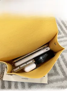 Top view of yellow felt crossbody bag showing interior capacity with phone and accessories