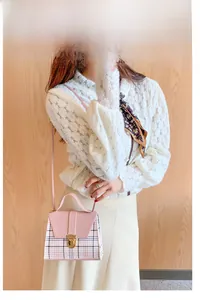 Detail of pink flap and plaid pattern on a mini trapezoid crossbody bag with gold snap