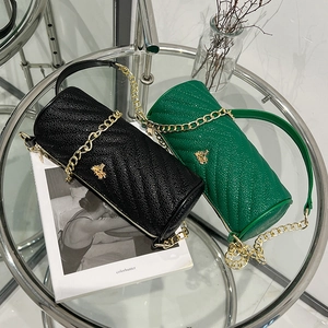 Cylindrical leather bags with tree ornaments in black and green on a glass table