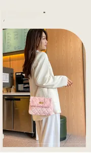 Detailed view of pink plush crossbody bag with diamond quilting and gold chain strap