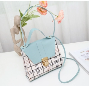 Detail view of plaid patterned handbag featuring light blue flap and gold metallic clasp