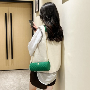 Green cylindrical crossbody bag with V-shaped quilting and gold chain strap