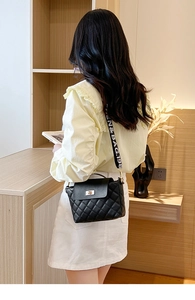 Détail du sac bandoulière matelassé noir avec fermoir rotatif et large sangle lettrée