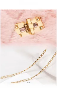 Macro detail of plush pink bag featuring a gold pyramid turn-lock and polished chain strap