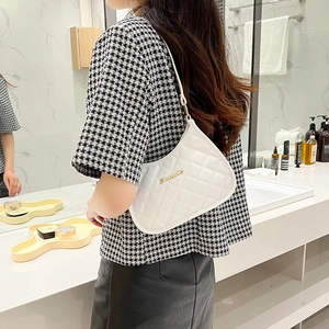 Chic white quilted faux leather underarm bag with gold logo on a model's shoulder