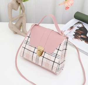 Detail view of pink vegan leather and plaid handbag with gold clasp and top handle