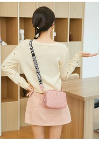 Pink quilted crossbody bag with metal butterfly and jacquard strap shown on model