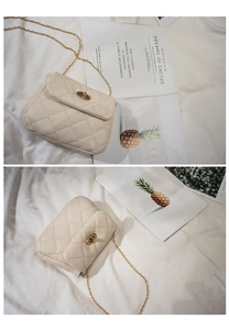 Close-up of quilted cream faux leather bag featuring a gold chain strap and turn-lock