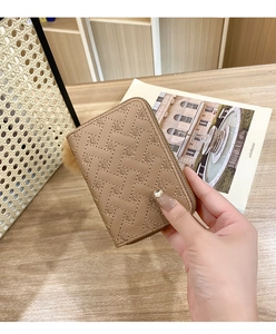 Gros plan du mini sac en cuir marron avec texture cœur tressée et breloque pompon