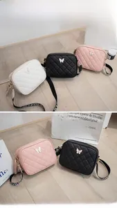 Close-up of quilted crossbody bag with metal butterfly clasp and tassel zipper detail