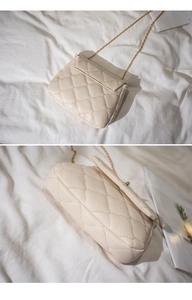 Detailed view of the creamy white quilted texture and golden chain on this crossbody bag