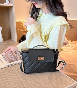 Détail d'un sac à bandoulière matelassé noir avec fermoir doré et sangle jacquard