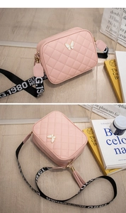 Close-up of pink quilted crossbody bag with butterfly buckle and woven logo strap
