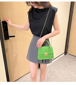 Green crocodile pattern mini handbag with gold chain strap shown on fashion model