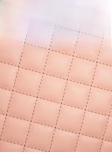 Close-up of pink quilted fabric with fine stitching and soft high-elastic sponge padding