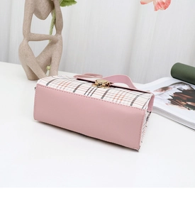 Detailed view of pink plaid crossbody bag with golden twist lock on a white surface