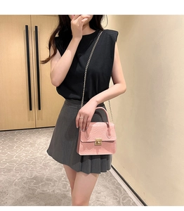 Detailed view of pink crocodile texture PU leather handbag with gold twist lock and chain strap