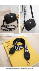 Close-up of black quilted shoulder bag with golden butterfly logo and jacquard strap