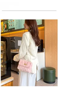 Close-up of pink plush shoulder bag with gold chain strap and quilted texture on model