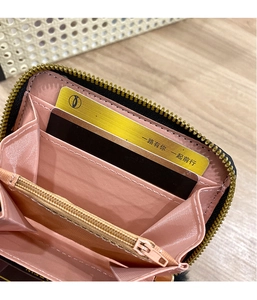 Detail of compact black wallet featuring pink lining, card slots and gold zipper