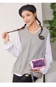 Détail du sac bandoulière rose transparent avec sangle lettrée porté par un mannequin