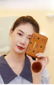 Brown litchi grain leather coin purse with LBS print and plush fur ball pendant detail