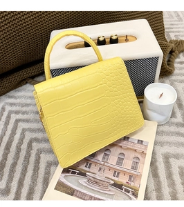 Detail of yellow crocodile texture leather handbag on stylish home decor background