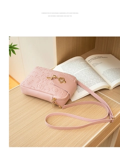 Detail of pink embossed PU leather phone bag with crown metal clasp on wooden desk