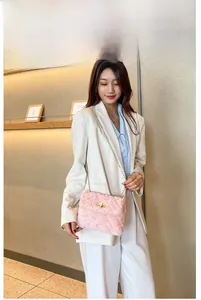 Close-up of pink plush shoulder bag with gold chain strap on white blazer outfit