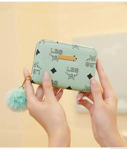Detail of mint green lychee pattern wallet with golden plate and plush fur pompom charm