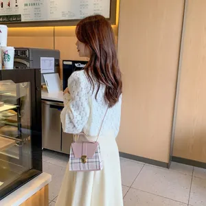 Pink leather and vintage plaid crossbody bag worn by a model in a casual cafe setting