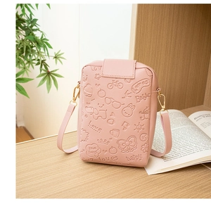 Detailed view of pink embossed phone bag with bicycle and heart patterns on wood surface