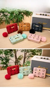 Detailed view of colorful pebbled leather coin purses with matching fluffy pom-pom charms