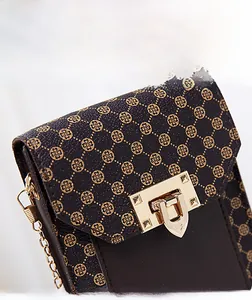 Detail of dark brown faux leather mini bag with gold clover print and metallic clasp