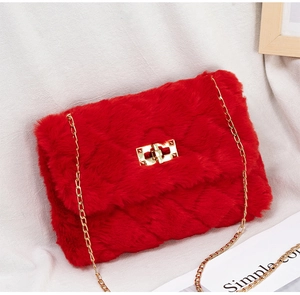 Detail of red faux fur shoulder bag featuring gold metal chain and rectangular twist lock
