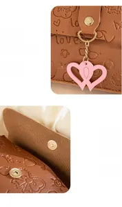 Close-up of brown embossed handbag with heart charm and magnetic snap button