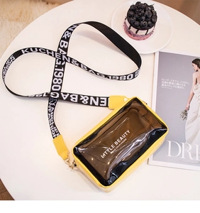 Détail du sac bandoulière transparent en PVC jaune et noir avec large sangle lettrée