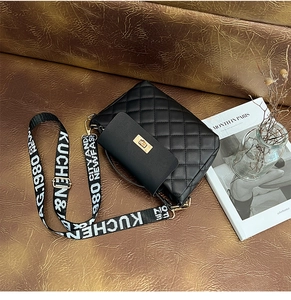 Détail d'un sac seau noir matelassé avec fermoir doré et bandoulière en toile tissée
