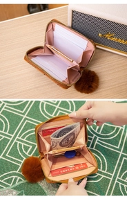 Detail view of brown textured leather coin purse with pink interior and fur ball charm