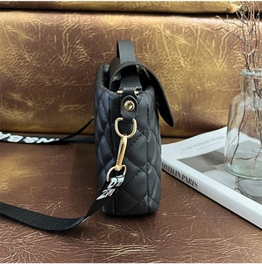 Détail du sac à bandoulière matelassé noir avec boucles dorées et sangle en tissu