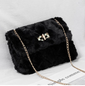Close-up of black faux fur shoulder bag with golden metal twist lock and chain strap